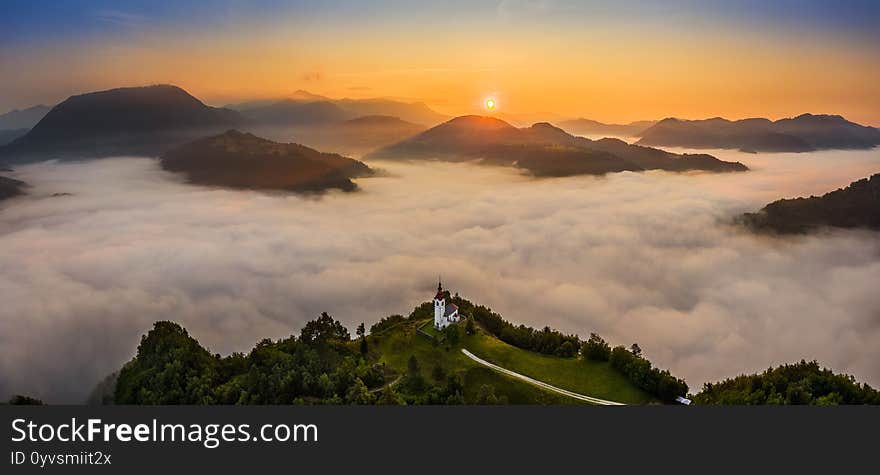 Sebrelje, Slovenia - Aerial panoramic drone view of the beautiful hilltop church of St.Ivan Sv. Ivan Cerkev at sunrise with fog