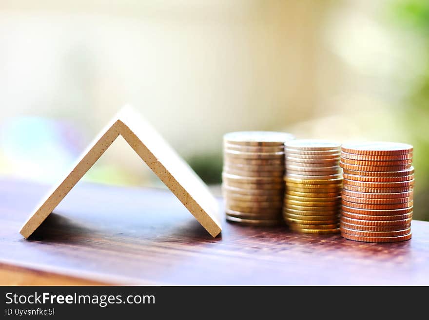 Coins stacking with small wood roof ,home loan concept blur background.