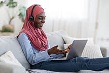 Online Business Meeting. Black Muslim Lady Using Headset And Laptop At Home Royalty Free Stock Photography