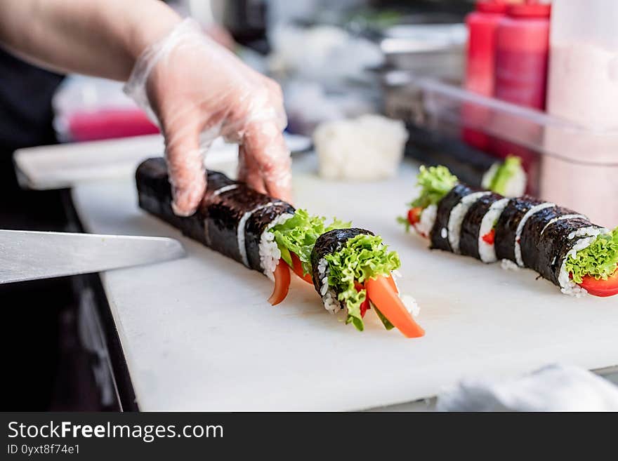 Sushi chef slicing rolls