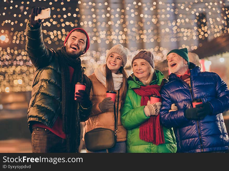 Photo of big family four members x-mas gathering hold mug make, selfie telephone videocall wear outerwear hat scarf coat glove generation night street park magic illumination outdoors outside. Photo of big family four members x-mas gathering hold mug make, selfie telephone videocall wear outerwear hat scarf coat glove generation night street park magic illumination outdoors outside