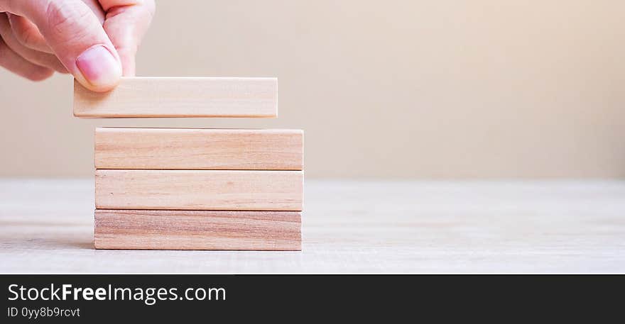 Businessman hand placing or pulling wooden block on the tower. Business planning, Risk Management, Solution, Insurance and strategy Concepts