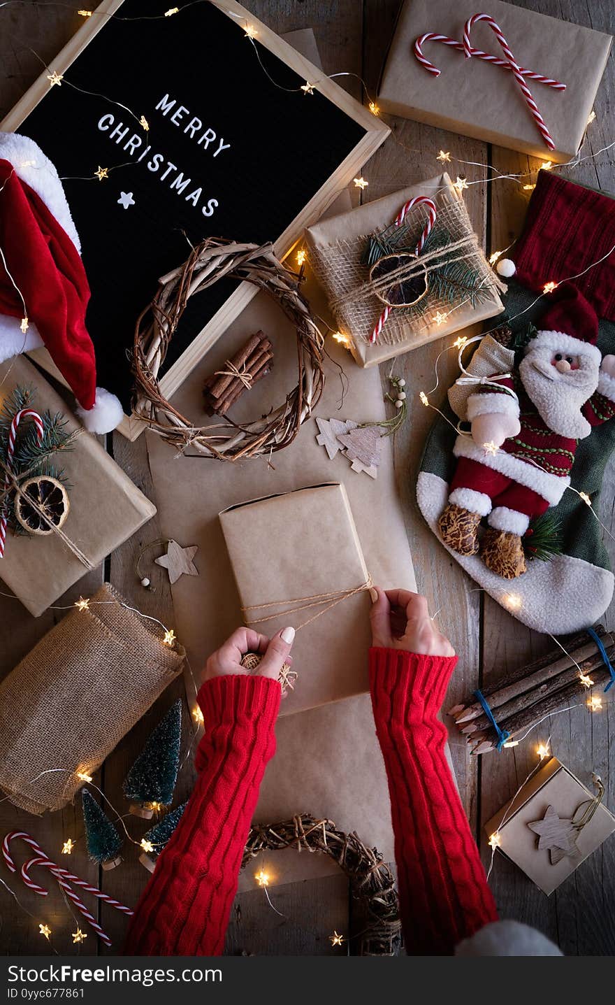 Zero waste and eco friendly christmas concept. Female hands wrapping christmas gifts in craft paper top view flat lay