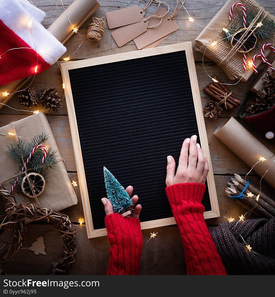 Zero waste and eco friendly christmas concept. Female hands holding blank letter board with christmas gifts and eco friendly decorations top view flat lay