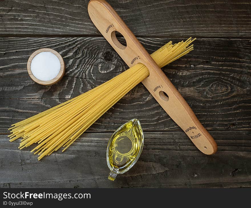 Spaghetti wooden measure, olive oil and salt on wooden table. Overhead shot. Spaghetti wooden measure, olive oil and salt on wooden table. Overhead shot