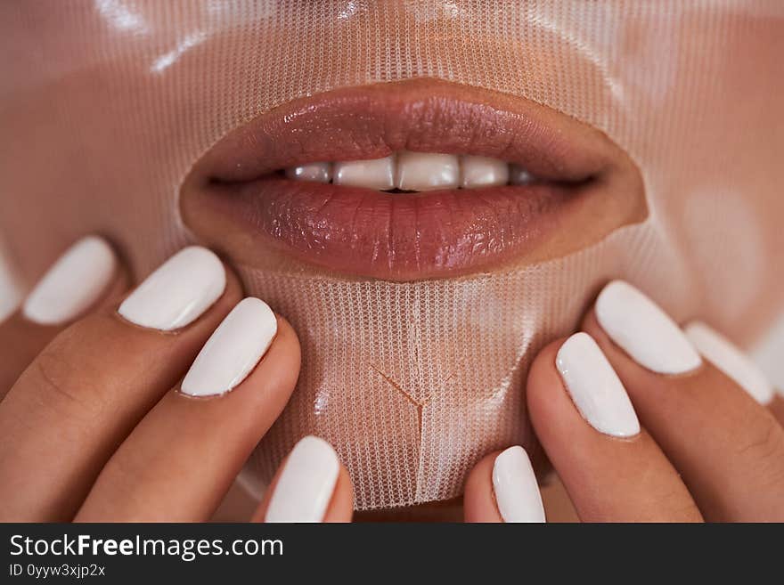 Beautiful woman with collagen mask on face. Woman applying a mask stroking her hands in the mouth area. Beautiful woman with collagen mask on face. Woman applying a mask stroking her hands in the mouth area