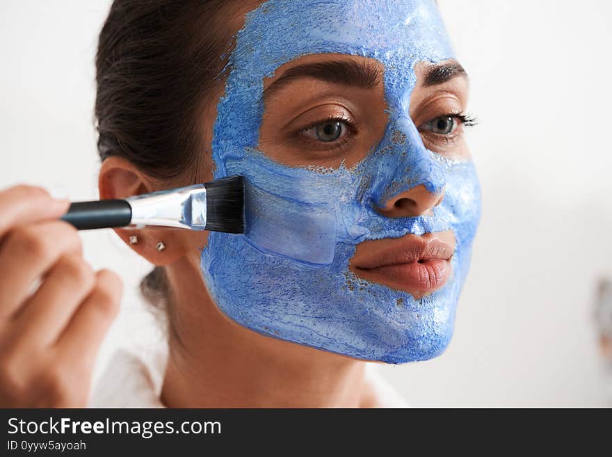 Happy woman putting diligently mask on her face. Beauty and health care concept. Happy woman putting diligently mask on her face. Beauty and health care concept