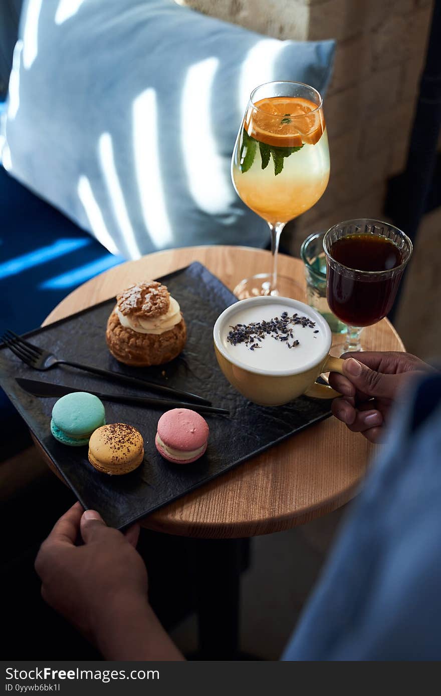 Waiter serves coffee and cakes to the client