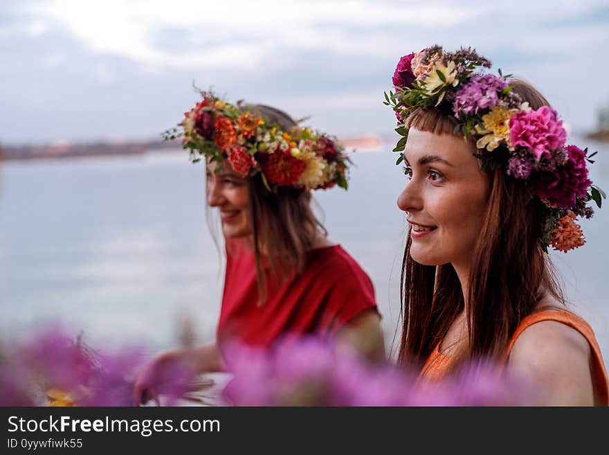 Two young and lovely girls in flower wreaths in nature. Ancient pagan origin celebration concept. Summer solstice day. Mid summer