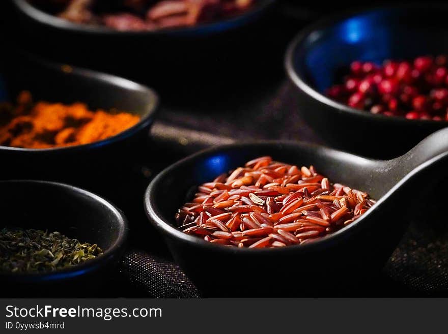 Brown/Red rice seeds in a spoon With various spices In low light conditions, rice is ready to be cooked.