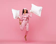 Excited Woman In Pajama Jumping With Pillow Royalty Free Stock Image