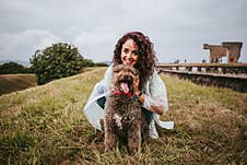 A Pretty Young Woman With A White Rain Jacket Petting And Playing With Her Spanish Water Dog In A Rainy Day In The North Of Spain Stock Photography