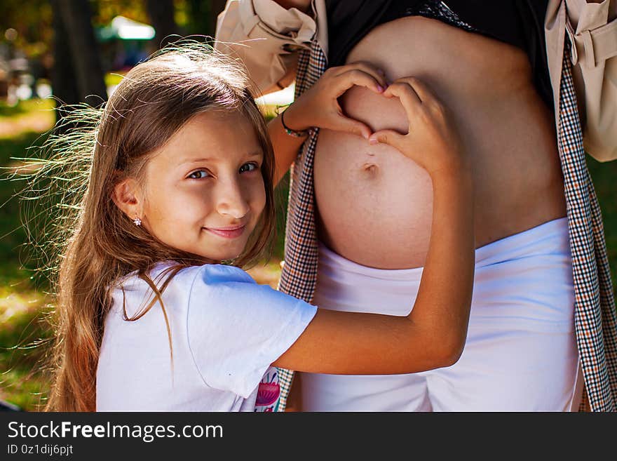 Happy Pregnant woman with her cute daughter in autumn  park. Happy Pregnant woman with her cute daughter in autumn  park