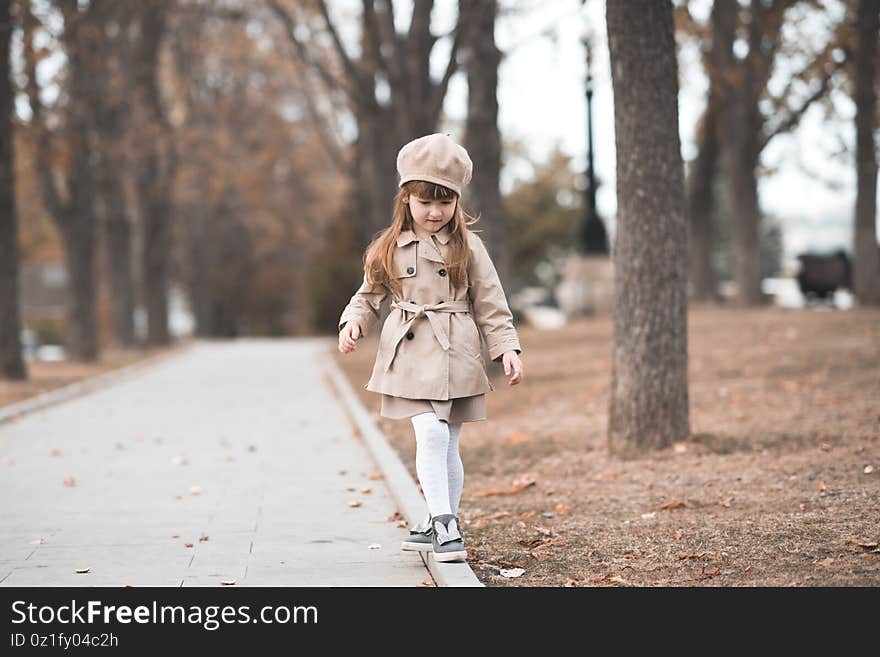 Stylish child girl 2-3 year old wearing trendy beige trench coat and beret walking in autumn park over nature background closeup. Fall season. Childhood. Stylish child girl 2-3 year old wearing trendy beige trench coat and beret walking in autumn park over nature background closeup. Fall season. Childhood