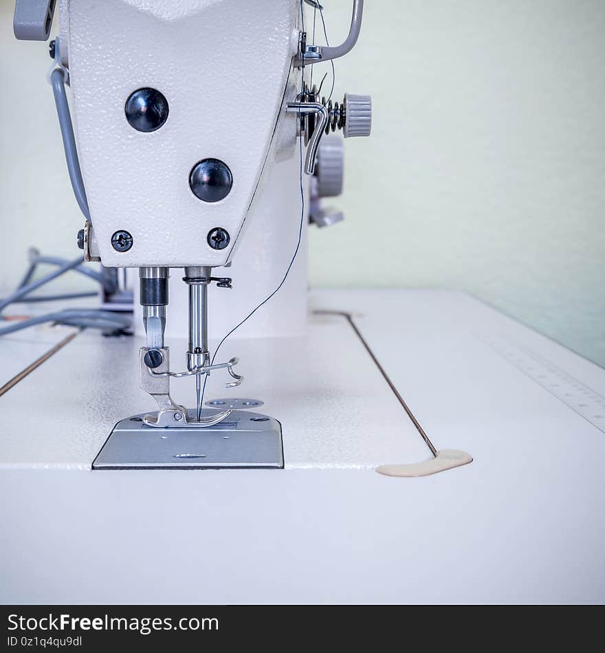 Sewing machine. In the foreground a mechanism with a needle and thread. Front view