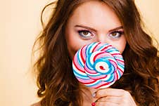 Woman Holds Colorful Lollipop Candy In Hand, Covering Face Royalty Free Stock Images