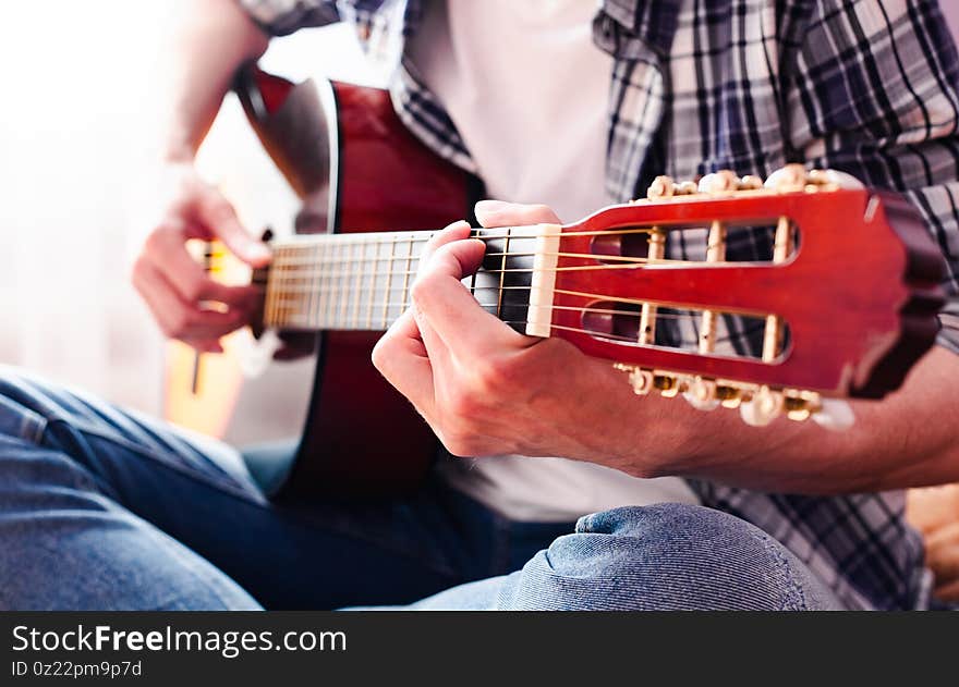 Young Man In Checkered Shirt Playing Guitar. Close-up