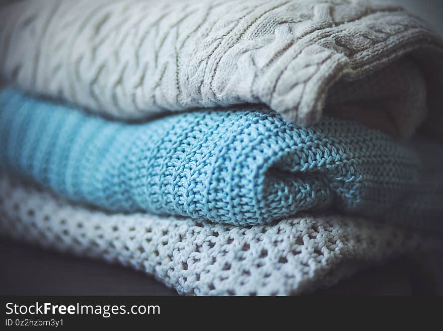 Three different wool warm sweaters with patterns are stacked in a pile. Cold days of winter. Warm clothing