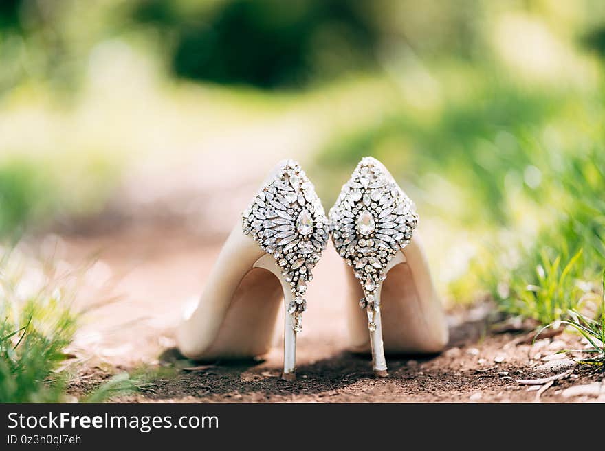 Bride`s shoes with a backdrop decorated with stones on the ground in nature with shallow depth of field.