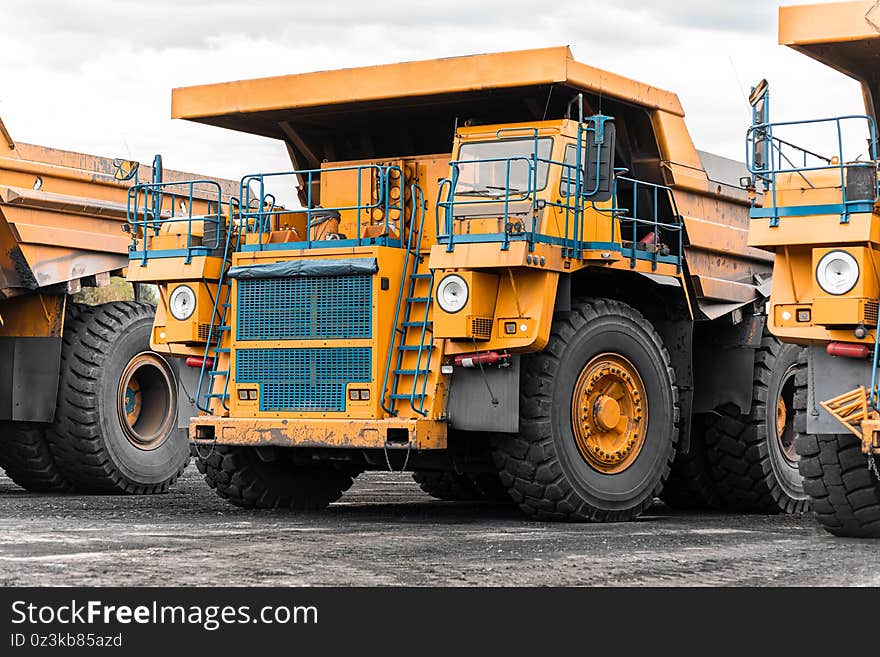 Large quarry dump truck. Big yellow mining truck at work site. Loading coal into body truck. Production useful minerals