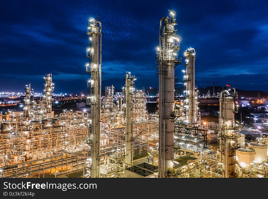 Industrial area oil and gas products refinery plants and stores pipeline at twilight over lighting with blue sky background in Thailand aerial view. Industrial area oil and gas products refinery plants and stores pipeline at twilight over lighting with blue sky background in Thailand aerial view