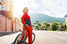 Sports Lifestyle. Beautiful Smiling Young Woman In Sportswear Posing Sitting On A Bicycle. Rear View. In The Background, An Empty Royalty Free Stock Photography