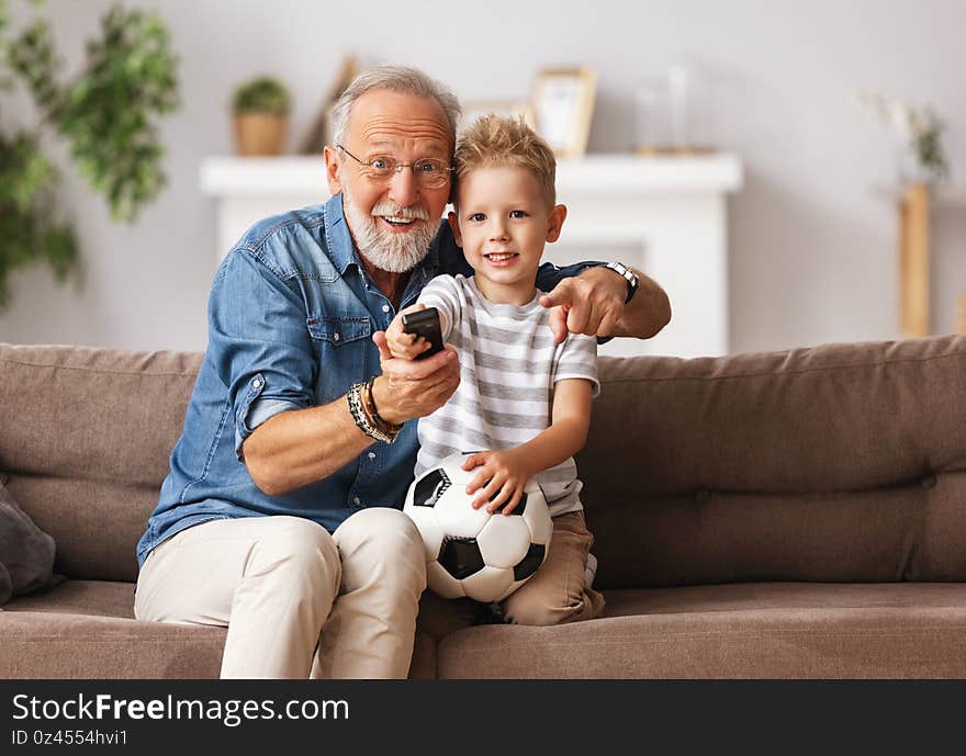 Cheerful grandfather and grandson watching football match