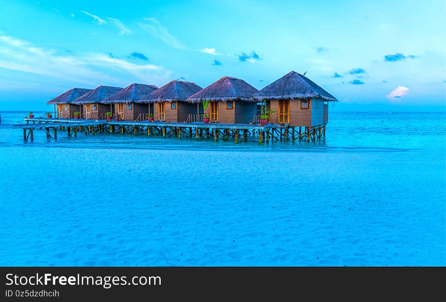 Wooden bridges leading to the huts on the shores of the tropical, warm sea. Maldives. Tourism concept.