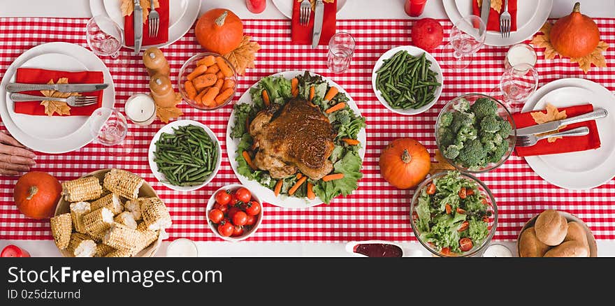 Panoramic shot of table with salad, glasses, candles, vegetables, pepper mill, corn, salt mill and pumpkins in Thanksgiving day