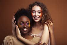 Two Pretty Girls African And Caucasian Blond Posing Cheerful Together On Brown Background, Ethnicity Diverse Lifestyle Royalty Free Stock Images