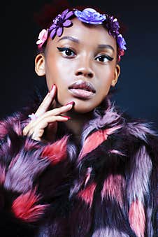 Young Pretty African American Woman In Spotted Fur Coat And Flowers Jewelry Posing On Black Background Stock Image