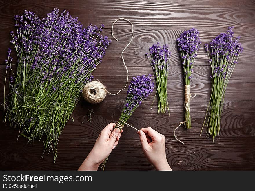 Florist at work - woman making lavender bouquets on wooden background