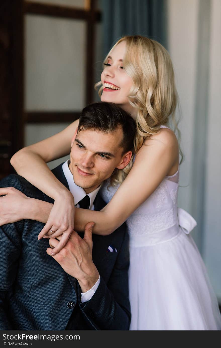 Cute Wedding Couple In The Interior Of A Classic Studio Decorated. They Kiss And Hug Each Other