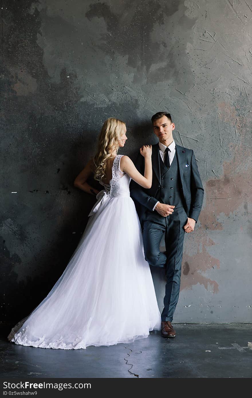 Cute wedding couple in the interior of a classic studio decorated. They kiss and hug each other