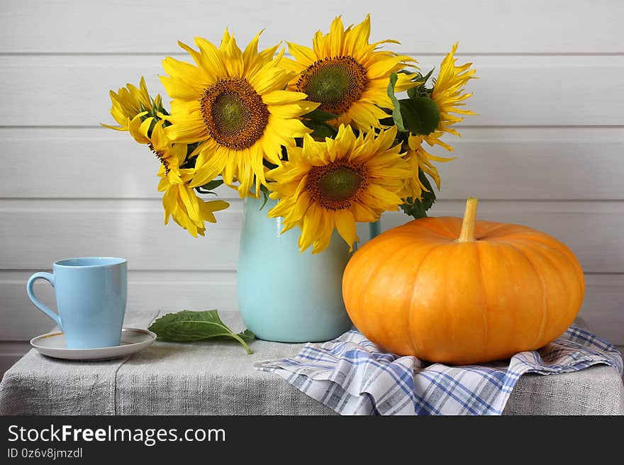 Light still life with a bouquet of sunflowers and a pumpkin