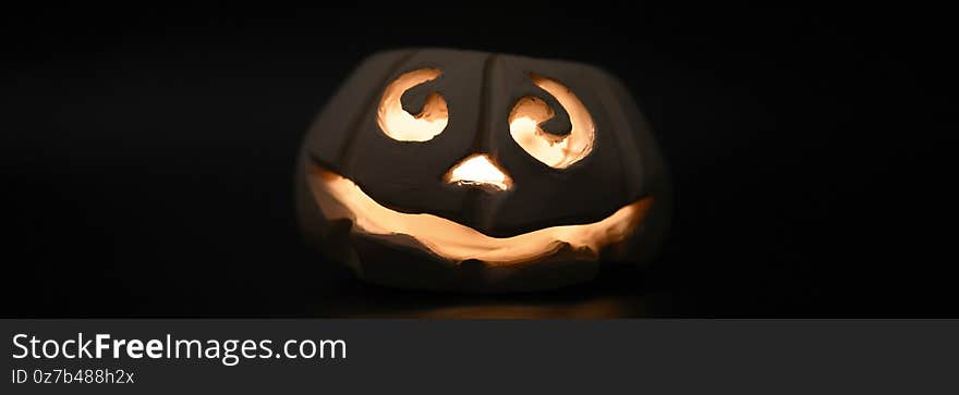 Glowing smiling face Halloween pumpkin, candle holder, isolated on night dark black background. banner.