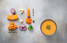 Autumn Pumpkin Soup In Dark Bowl And Ingredients For Cooking. Stock Photography