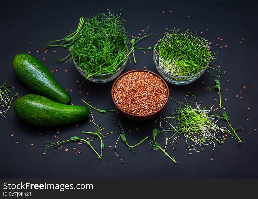 Microgreens: green peas and onion sprouts, flax seeds in glass bowls and avocado