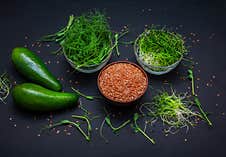 Microgreens: Green Peas And Onion Sprouts, Flax Seeds In Glass Bowls And Avocado Stock Photos