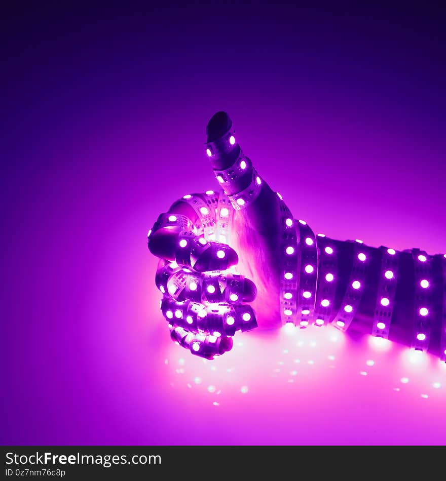 Thumbs up hand covered with purple led lights, illuminated background, close-up view