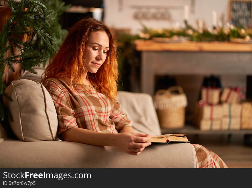 A cute girl is reading a book in a warm and cozy atmosphere. Relaxation and privacy concept