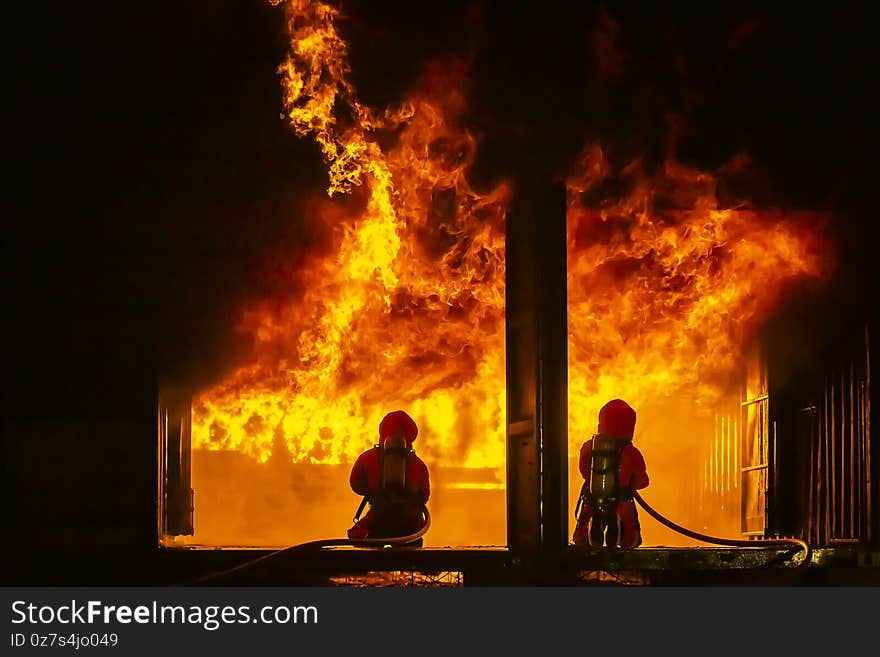 Firefighter training, fireman using water and extinguisher to fighting with fire flame in an emergency situation., under danger situation all firemen wearing fire fighter suit for safety.