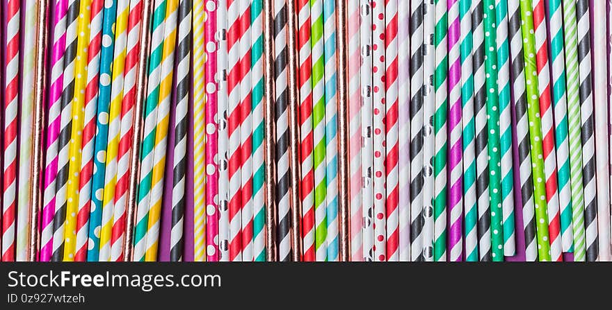 Top view of bright striped green, yellow, pink and blue cocktail straws as attributes of party. Banner for website. Top view of bright striped green, yellow, pink and blue cocktail straws as attributes of party. Banner for website