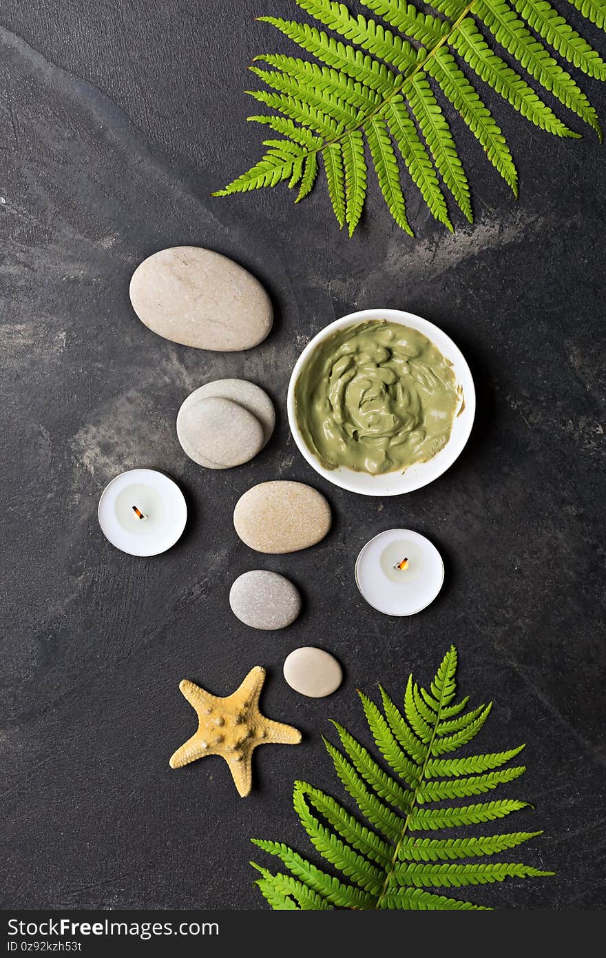Spa background with cosmetic clay, sea stones and aroma candles