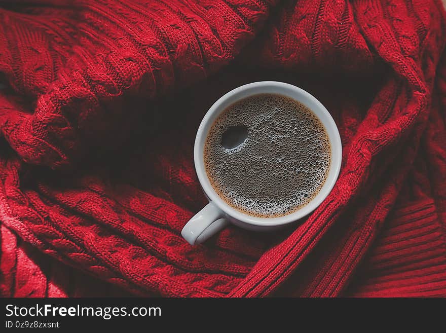 Coffee top view. black coffee in a white mug on Red Sweater background. winter time concept.