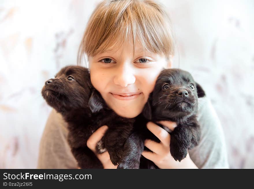 Girl holding and hugging two of the puppies are black in color is happy and smiling