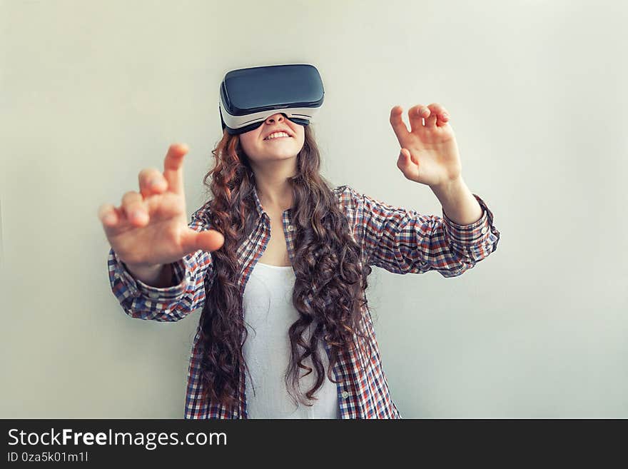 Smile young woman wearing using virtual reality VR glasses helmet headset on white background. Smartphone using with virtual reality goggles. Technology, simulation, hi-tech, videogame concept