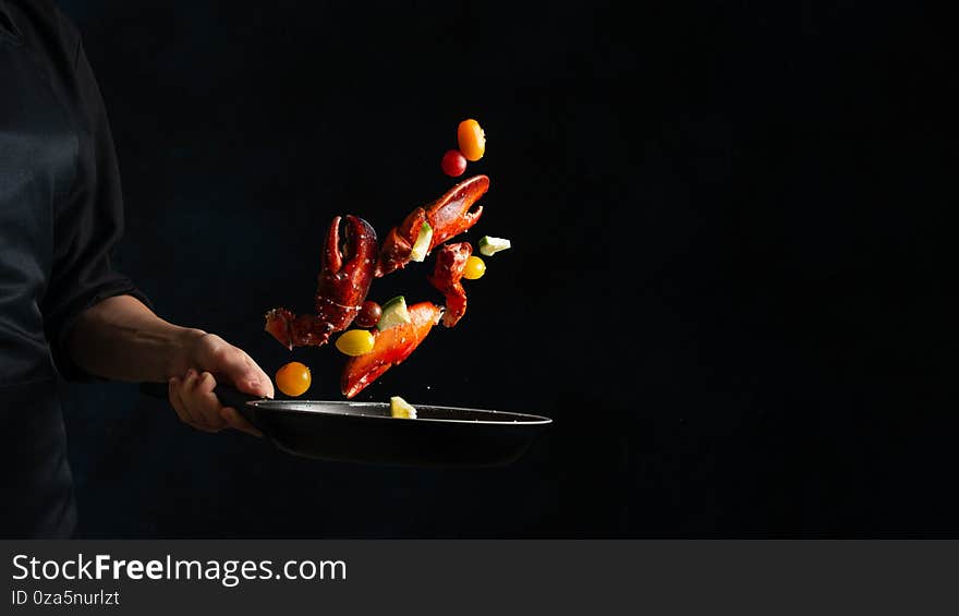 Close-up view of the professional chef tossed crab lags with lime in frying pan on black background. Backstage of cooking delicious meal for dinner. Seafood concept. Frozen motion. Asian cuisine.