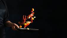 Close-up View Of The Professional Chef Tossed Crab Lags With Lime In Frying Pan On Black Background. Backstage Of Cooking Stock Photography