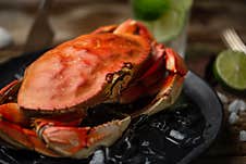 Close-up View Of Tasty Cooked Crab On Black Round Plate With Ice Cubes Served With Lime And Seashells On Rustic Wooden Table, Stock Images